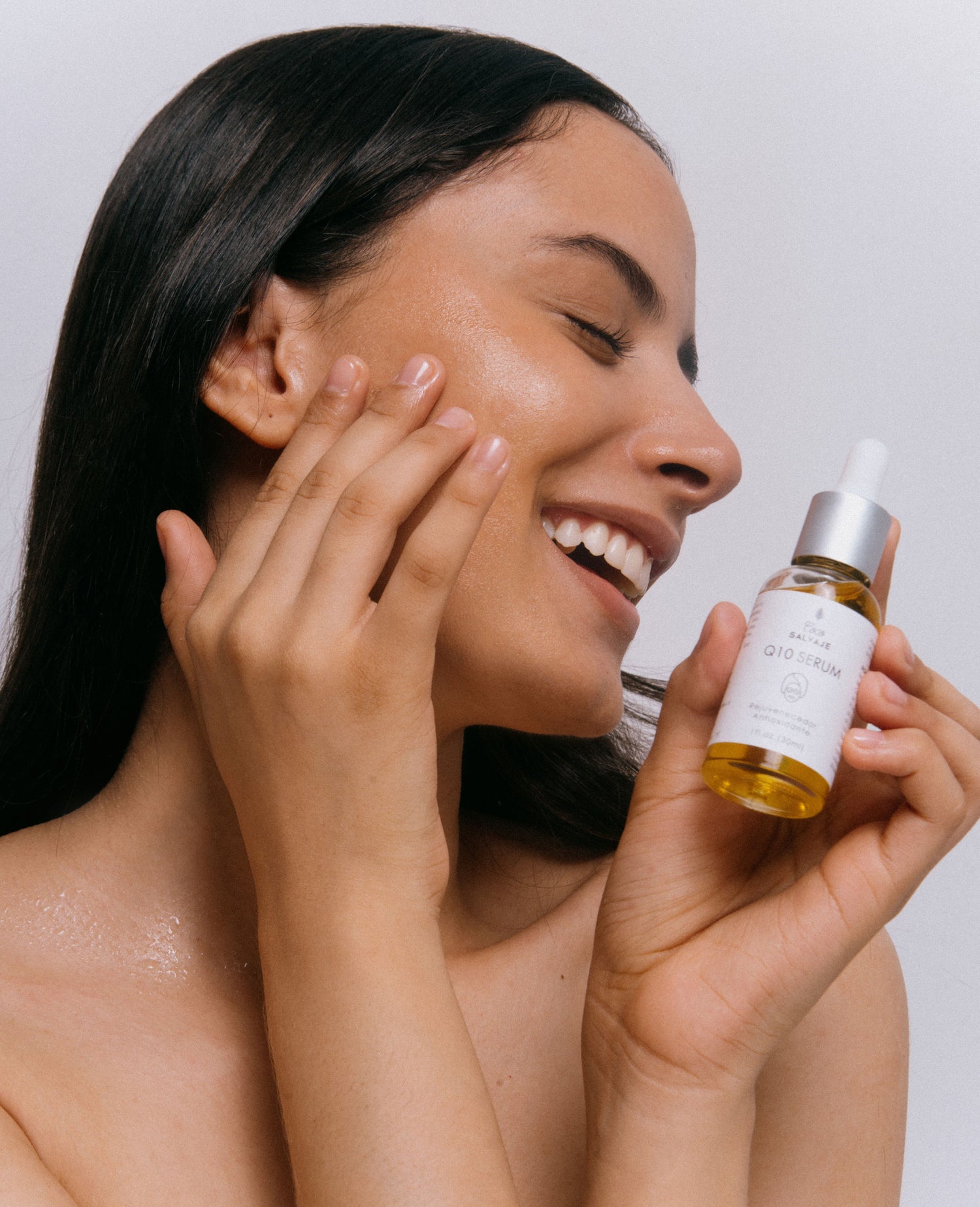 Model holding Q10 Serum smiling.